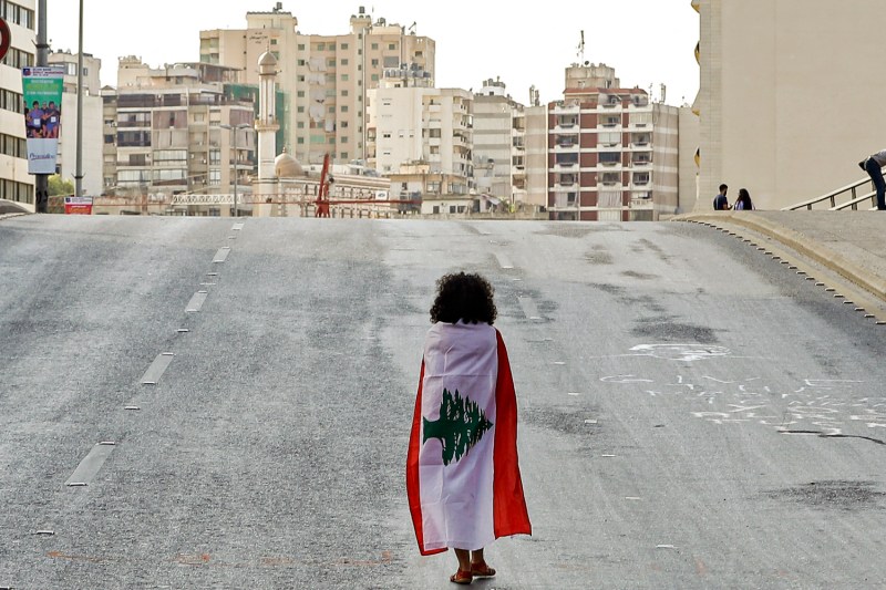 A Lebanese woman protester walks draped in a national flag along the Fuad Chehab avenue, near the Martyrs' Square, in the centre of the capital Beirut on October 29, 2019 on the 13th day of anti-government protests.