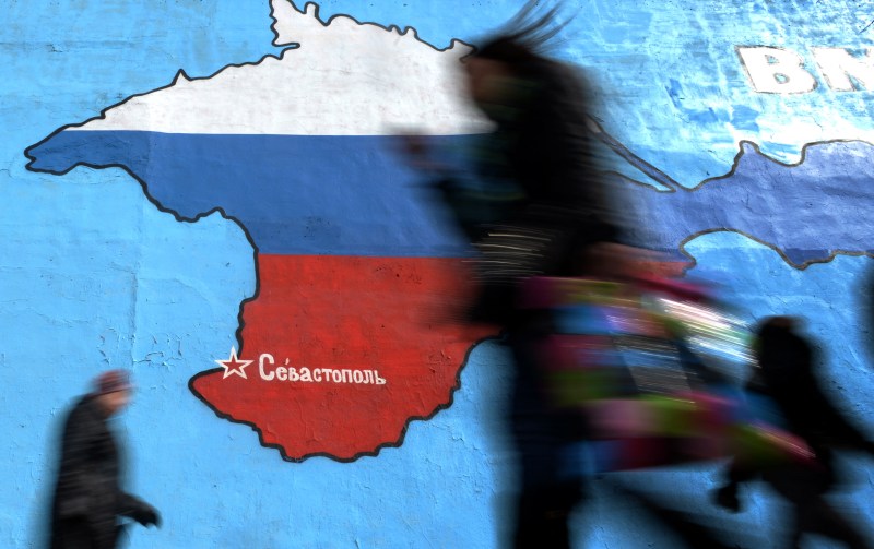 Pedestrians walk past an wall painting depicting a map of Crimean peninsula bearing the colours of Russia's national flag  in Moscow, on March 31, 2014.