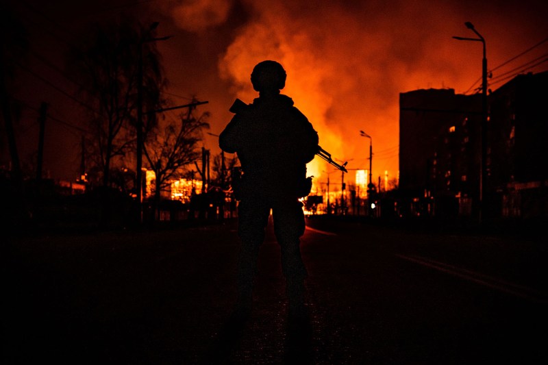 A member of the Ukrainian special forces is seen in silhouette as a gas station burns after Russian attacks on the city of Kharkiv on March 30, 2022, during Russia's invasion of Ukraine.