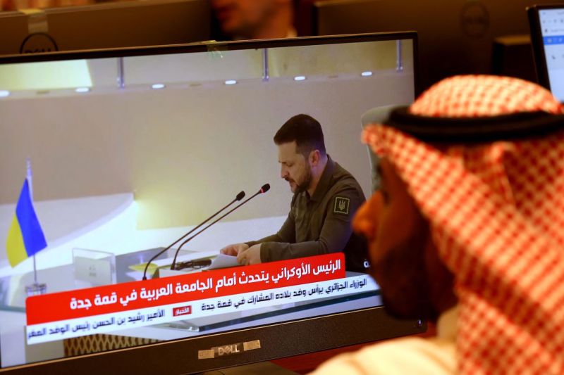 Media delegates watch Ukrainian President Volodymyr Zelensky, shown on a TV screen, address the Arab League summit in Jeddah.