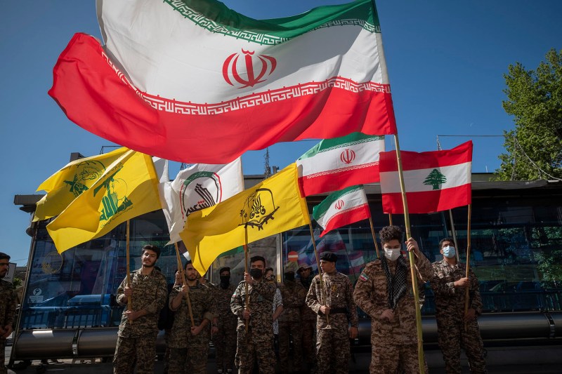 Members of Iran’s Basij force hold the flags of Iran, Lebanon, and proxy forces including Hezbollah during a rally commemorating Quds Day.