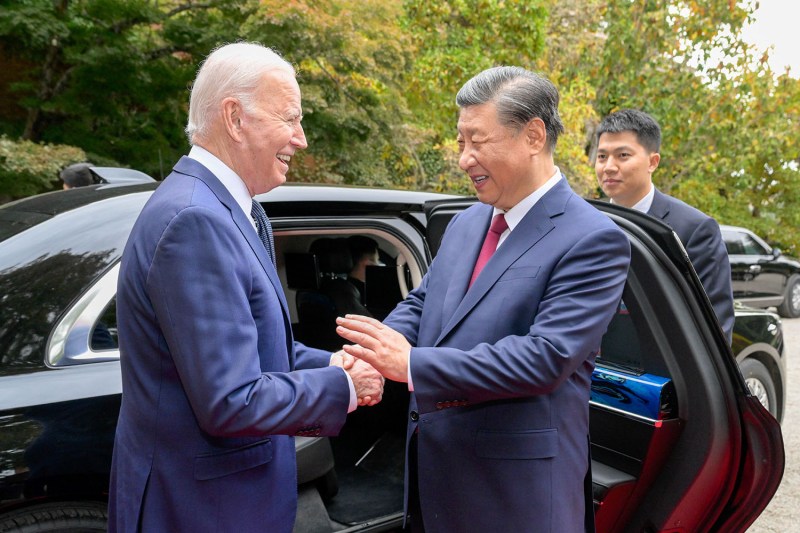 Joe Biden and Xi Jinping smile and shake hands near a car