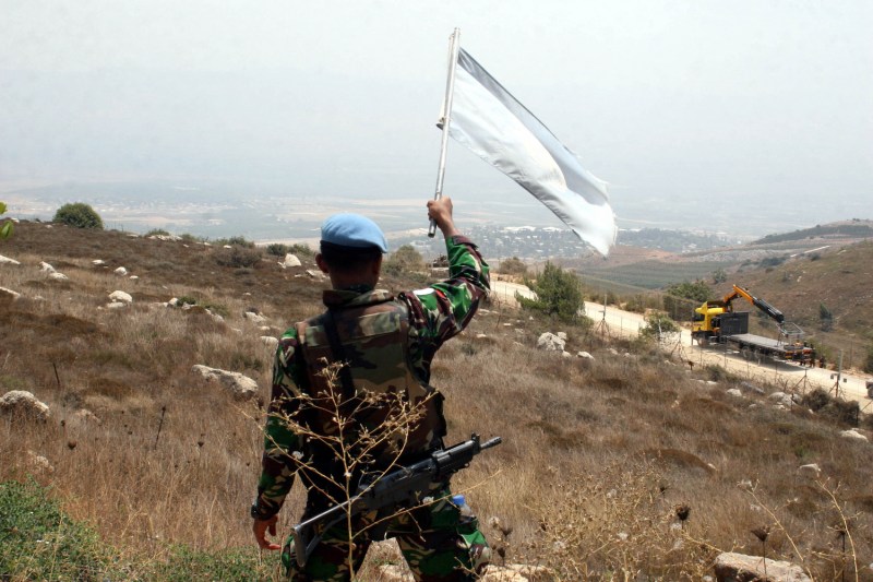 An Indonesian soldier serving with the UNIFIL (United Nations Interim Force in Lebanon) waves the U.N. flag at Israeli soldiers in the village of Adaisseh, Lebanon on August 3, 2010.