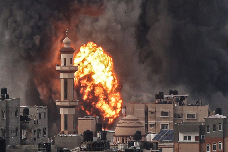A fireball erupts behind a turreted building as smoke fills the sky after an Israeli strike over Rafah in the southern Gaza Strip.