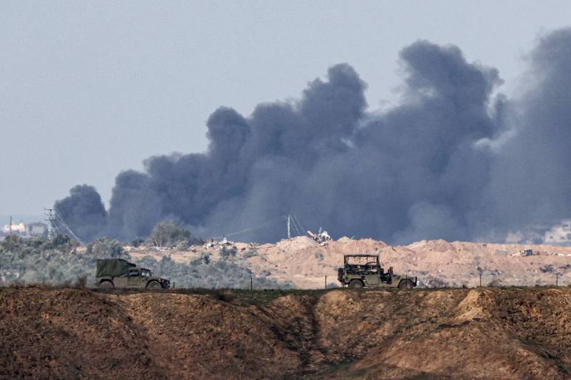 Israeli military vehicles drive near the border with the Gaza Strip on Dec. 6 as black smoke rises in the Palestinian territory amid continuing battles between Israel and the militant group Hamas.