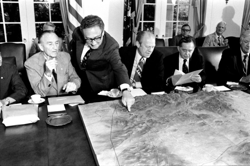 Secretary of State Henry Kissinger (standing) points at a map of the Sinai Peninsula during a meeting with President Gerald R. Ford (C) Congressional Leaders in the Cabinet Room on Sept. 4, 1975.