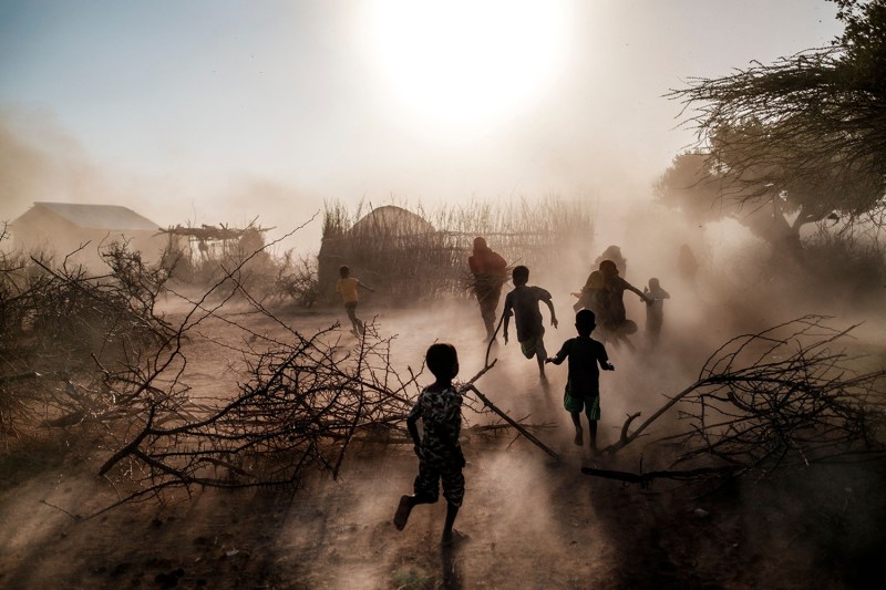 Children and women run among a cloud of dust in Ethiopia