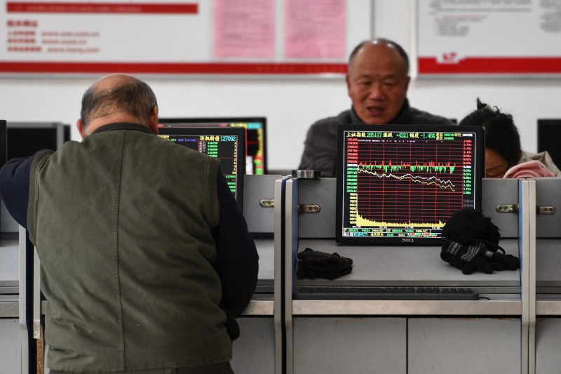 Investors look at screens showing stock market movements at a securities company in Fuyang, China, on Jan. 17.