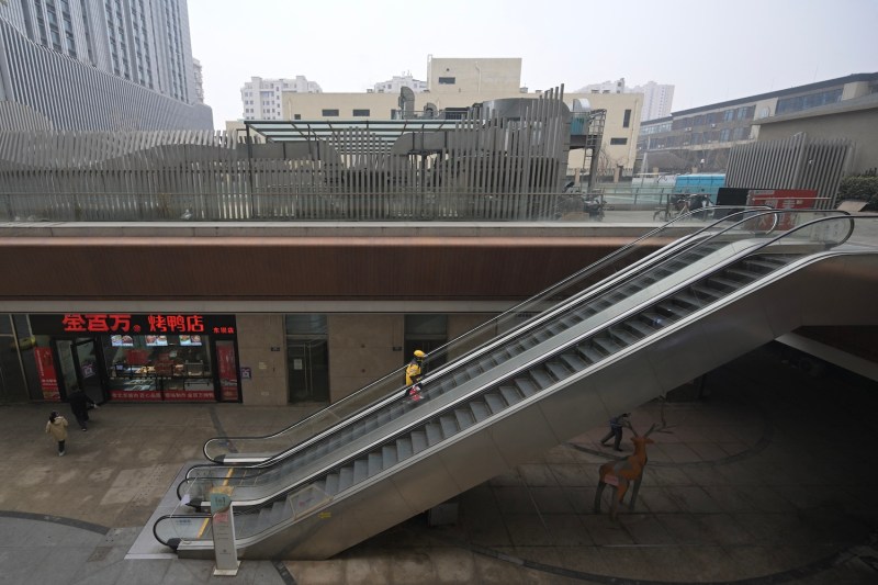 A delivery worker uses an escalator at a partially operating Evergrande commercial complex in Beijing.