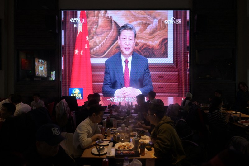 People eat at a restaurant as a screen broadcasts Chinese President Xi Jinping's New Year's speech in Beijing.