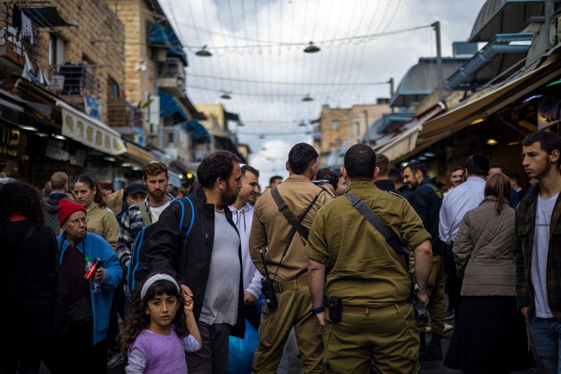 Armed soldiers walk among shoppers at the Machane Yehuda Market in Jerusalem.