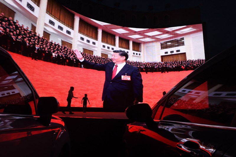Children play near a large screen showing images of Chinese President Xi Jinping.