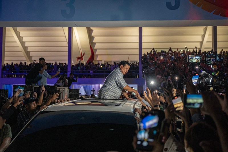 Indonesian presidential candidate Prabowo Subianto, leaning out of the roof of a car, shakes hands with supporters at an event in Jakarta.