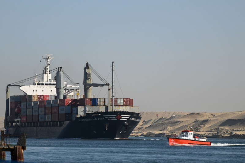 A large container ship is shown next to a smaller orange-red ship.