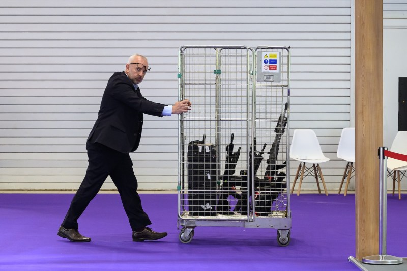 A man pushes a cage of display firearms toward a manufacturer's stand for the Defence and Security Equipment International (DSEI) fair in London on Sept. 12, 2023.