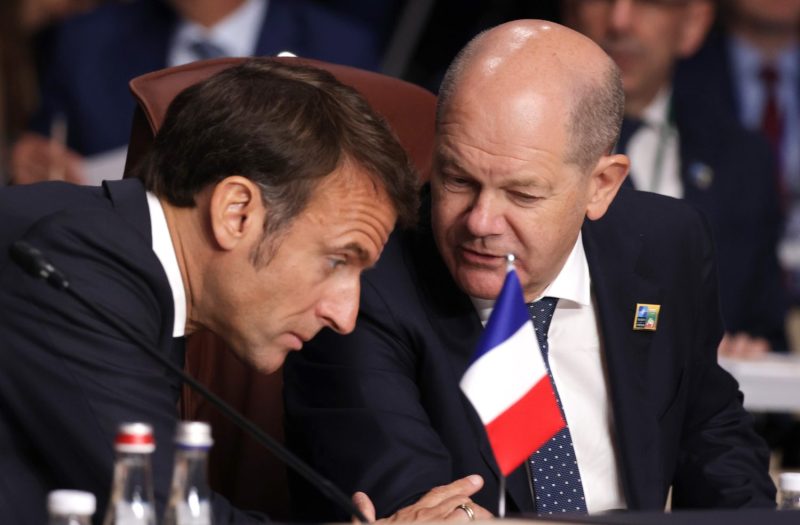 French President Emmanuel Macron and German Chancellor Olaf Scholz huddle at the annual NATO Summit in Vilnius, Lithuania, on July 11, 2023.