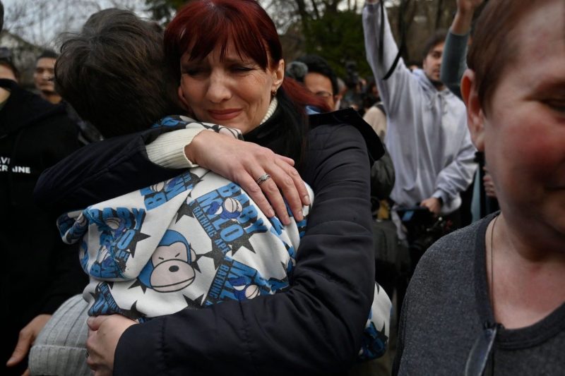 A Ukrainian mother hugs her son after a bus delivering him and more than a dozen other children from Russian-held territory arrives in Kyiv on March 22, 2023.