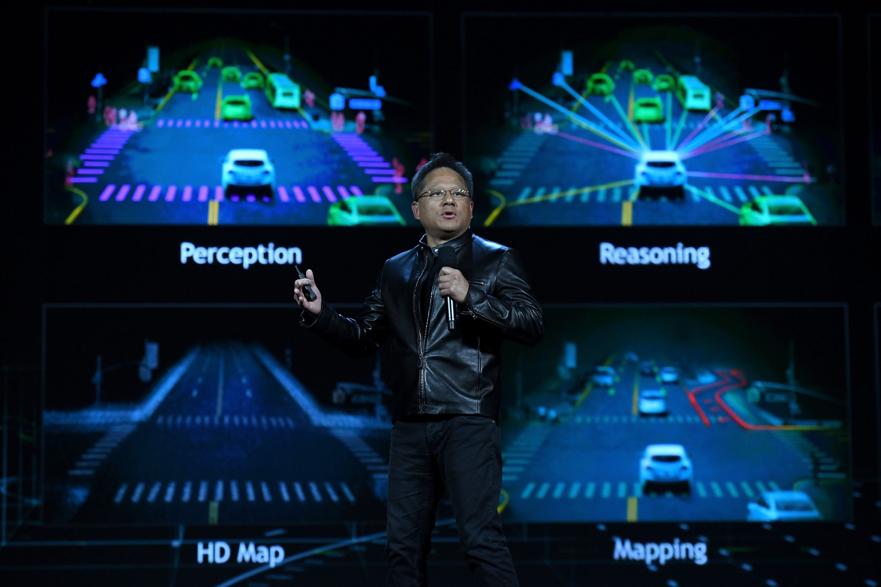 Jen-Hsun Huang speaks on stage against a backdrop of self-driving care technology.