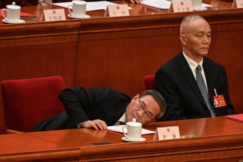 Chinese Premier Li Qiang leans down from his seat while attending the 14th National People's Congress at the Great Hall of the People in Beijing.