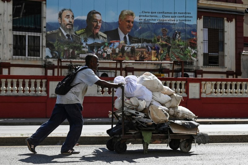 A Cuban man pushes a wheelbarrow of waste on a street in Havana on March 18.