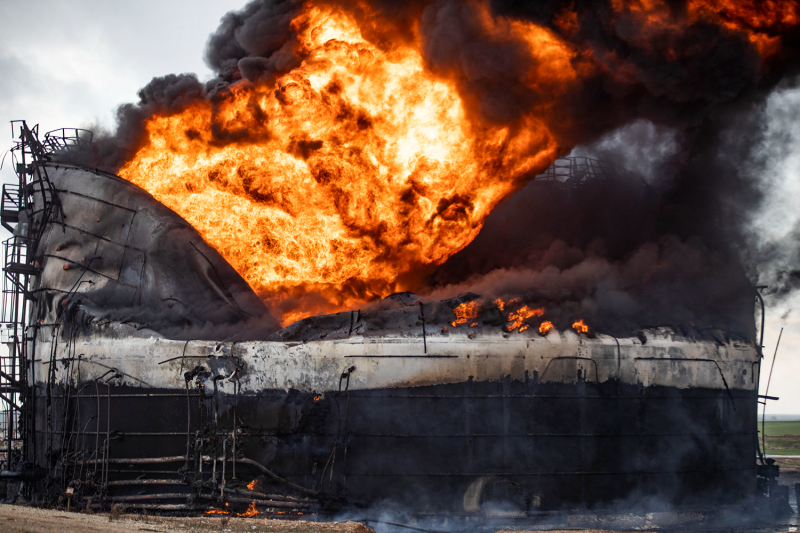 A massive orange conflagration of flames and thick smoke billows from a raging fire at a storage tank of al-Awda oil field.