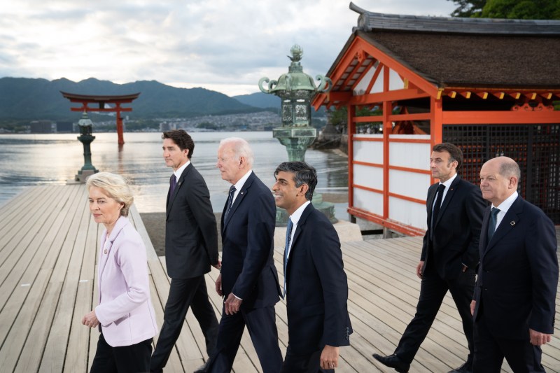 World leaders are shown walking on a pier by the water.