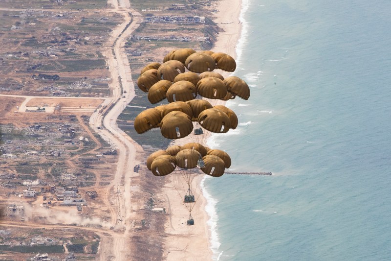 A cluster of parachutes dropping supplies is seen from above over the coast of the Gaza Strip.