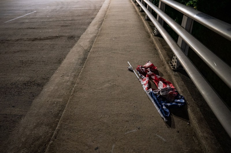 A ripped American flag rests abandoned along a road during a protest in response to the Republican National Convention being held in Charlotte, North Carolina.
