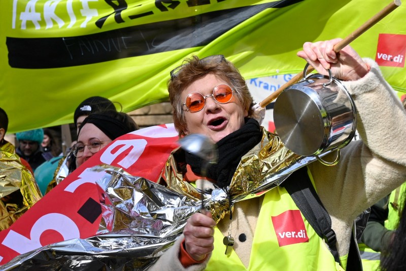 An employee of the public health care makes noise with a cooking pot as she takes part in a protest rally during a warning strike in Stuttgart, Germany, on March 13, 2023.