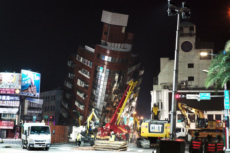 Emergency personnel stand in front of a partially collapsed building in Taiwan.