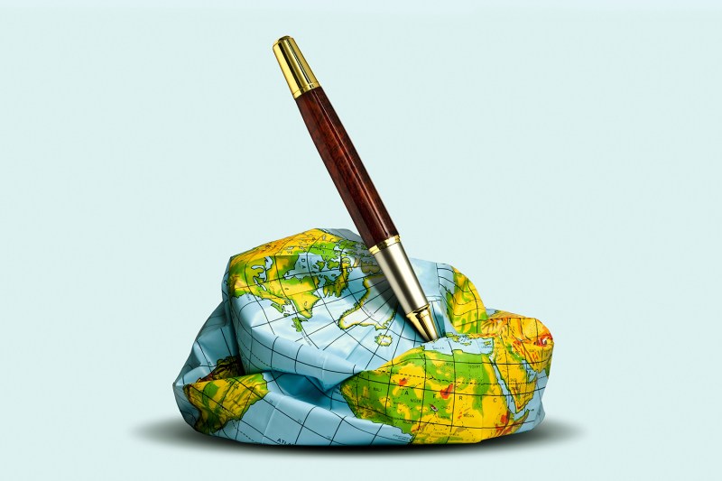 A photo illustration shows a deflated plastic globe with a pen speared into it.