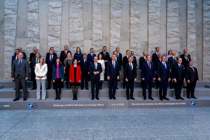 NATO's foreign ministers stand in business attire on stone steps in three rows facing forward.