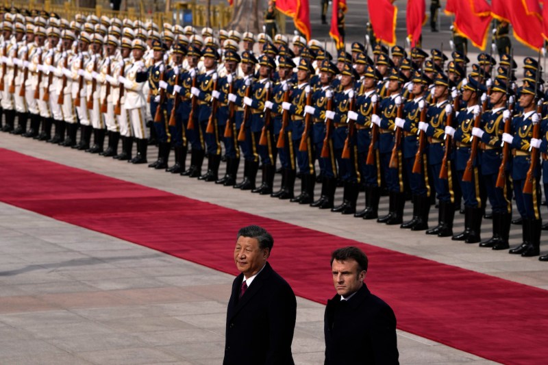 French President Emmanuel Macron walks with Chinese President Xi Jinping after inspecting an honor guard during a welcome ceremony outside the Great Hall of the People in Beijing.