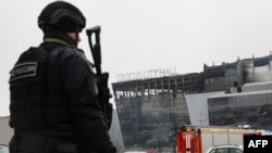 Сотрудник МВД напротив сгоревшего здания "Крокус Сити Холл" 23 марта 2024