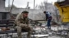 A Ukrainian serviceman smokes sitting on a bench as a local resident clears debris near a building damaged in a Russian air raid on the town of Orikhiv in the Zaporizhzhia region, Ukraine. (file photo)