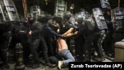 Forțele de ordine arestând un demonstrant pro-european la 1 mai, la Tbilisi. Criticii legii „agenților străini”, care a declanșat protestele repetate, spun că ea blochează parcursul european al țării. 