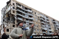 Мужчина играет на скрипке перед жилым домом в украинском городе Днепр, разрушенным в результате ракетного удара 14 января 2023 года