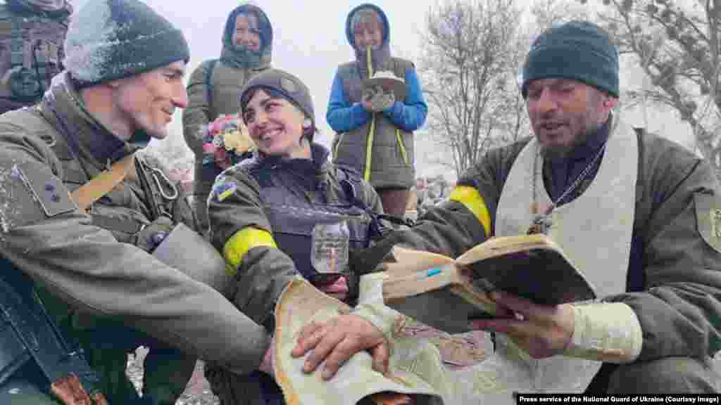 8 марта, свадьба двух бойцов Нацгвардии Украины (место неизвестно). Еще один молодой жених в Киеве, Виталий, которого нет на этом снимке, рассказал фотографу AFP, что решение жениться сейчас &ndash; это &quot;самый веселый и самый трудный шаг, который вы можете сделать&quot; из-за неопределенности войны. &quot;Ведь я могу в любой момент уйти на фронт&quot;, &ndash; говорит он.