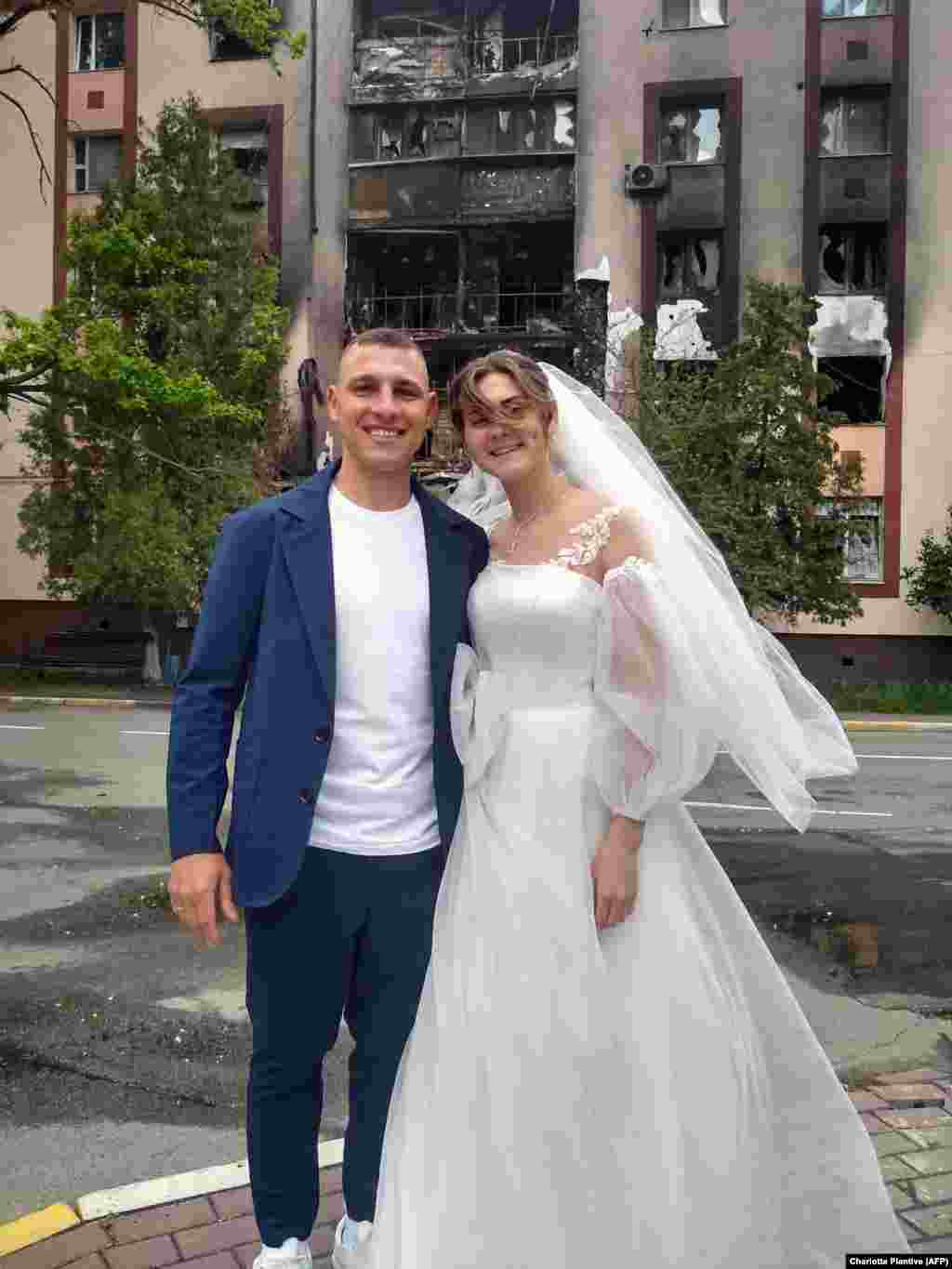 Михаил и Анастасия, женившиеся в Буче 26 мая, позируют перед разрушенным домом. ЗАГСы в Буче и соседнем городе Ирпень возобновили работу в мае после того, как российские войска прекратили наступление на Киев.