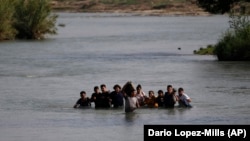 Мигранты, в основном из Никарагуа, пересекают реку Рио-Гранде, перебираясь в штат Техас. 20 мая 2022 года