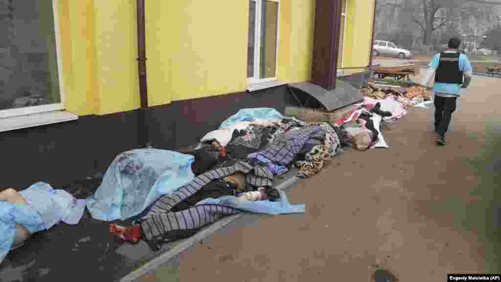 Russia -- A police officer walks past the bodies of people killed by shelling