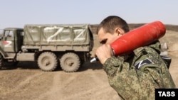 Военнослужащий "народной милиции" "ЛНР "держит агитационный снаряд, которым ведется стрельба из самоходных гаубиц "Гвоздика"