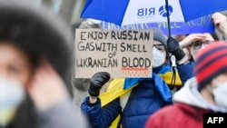 "Наслаждайтесь российским газом с запахом украинской крови" – плакат в руках участницы демонстрации в поддержку Украины в Германии