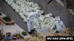 Медицинские работники готовят пакеты с едой для жителей многоквартирного дома, полностью заблокированных в квартирах из-за строгого карантина. Пекин, 28 ноября 2022 года
