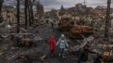 UKRAINE -- Vladyslava Liubarets (C), a Bucha resident, walks with her family past destroyed Russian military machinery, to meet her sister whom she did not see since the beginning of the Russian invasion, in Bucha, the town which was retaken by the Ukrain