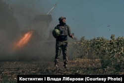 Украинский военный держит арбуз на фоне ракетной установки, ведущей огонь по позициям противника. Фото Влады и Константина Либеровых