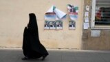 A woman walks past election campaign posters for the March 1 parliamentary election in downtown Tehran on February 22.