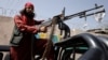 A Taliban fighter rides on a pickup truck mounted with a weapon in Kabul.