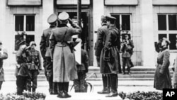 Военнослужащие нацистской Германии и СССР отдают честь немецком флагу со свастикой во время торжеств в рамках военного парада по случаю разделения земель, принадлежавших до этого Польше