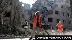 Workers clean up outside a building destroyed as a result of Russian shelling in Mykolayiv on August 2.